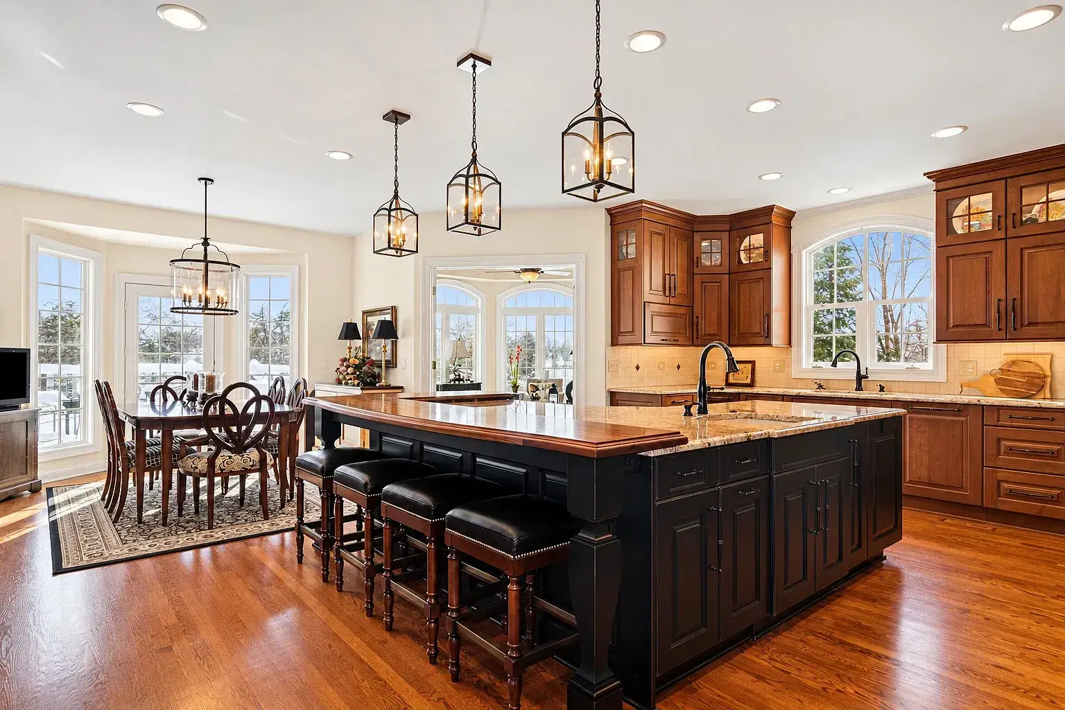Kitchen with a dark island, granite counters and lantern pendants